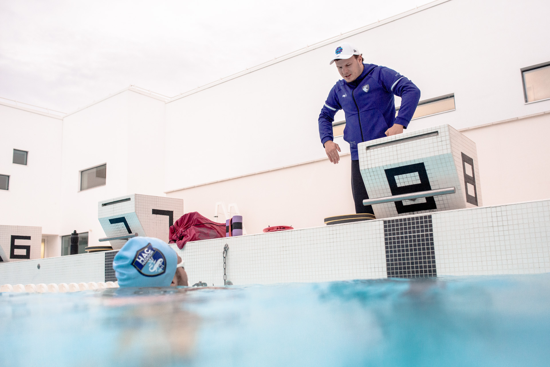 <strong>Le Coach</strong><br>Pour Cameron, la préparation,c’est avant tout un projet et une équipe pour l’épauler, cette équipe s’est construite au fil du temps et au fil de ses projets sportifs. Il y a d’abord Julien, le Coach, entraîneur au HAC Natation depuis plus de 2 ans. Son rôle est de proposer un plan de préparation suivi et réaliste en réponse au projet de Cameron.<br>Le mot du coach à propos du projet de Cameron : « C’est courageux, Cameron est un sprinter, il n’a pas le profil pour faire des longues distances. un long travail l’attend. » Actuellement, L’entraînement de Cameron, c’est une seule journée de repos et jusqu’à quinze heures d’entraînement par semaine, réparties entre la musculation, les séances en piscine et en mer. Mais l’équipe ne s’arrête pas là : elle réunit des compétences clés pour assurer la communication sur les réseaux sociaux et veiller au bien-être du nageur, tant sur le plan physique que mental.